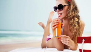 κοπέλα στην παραλία με ποτήρι χυμό.